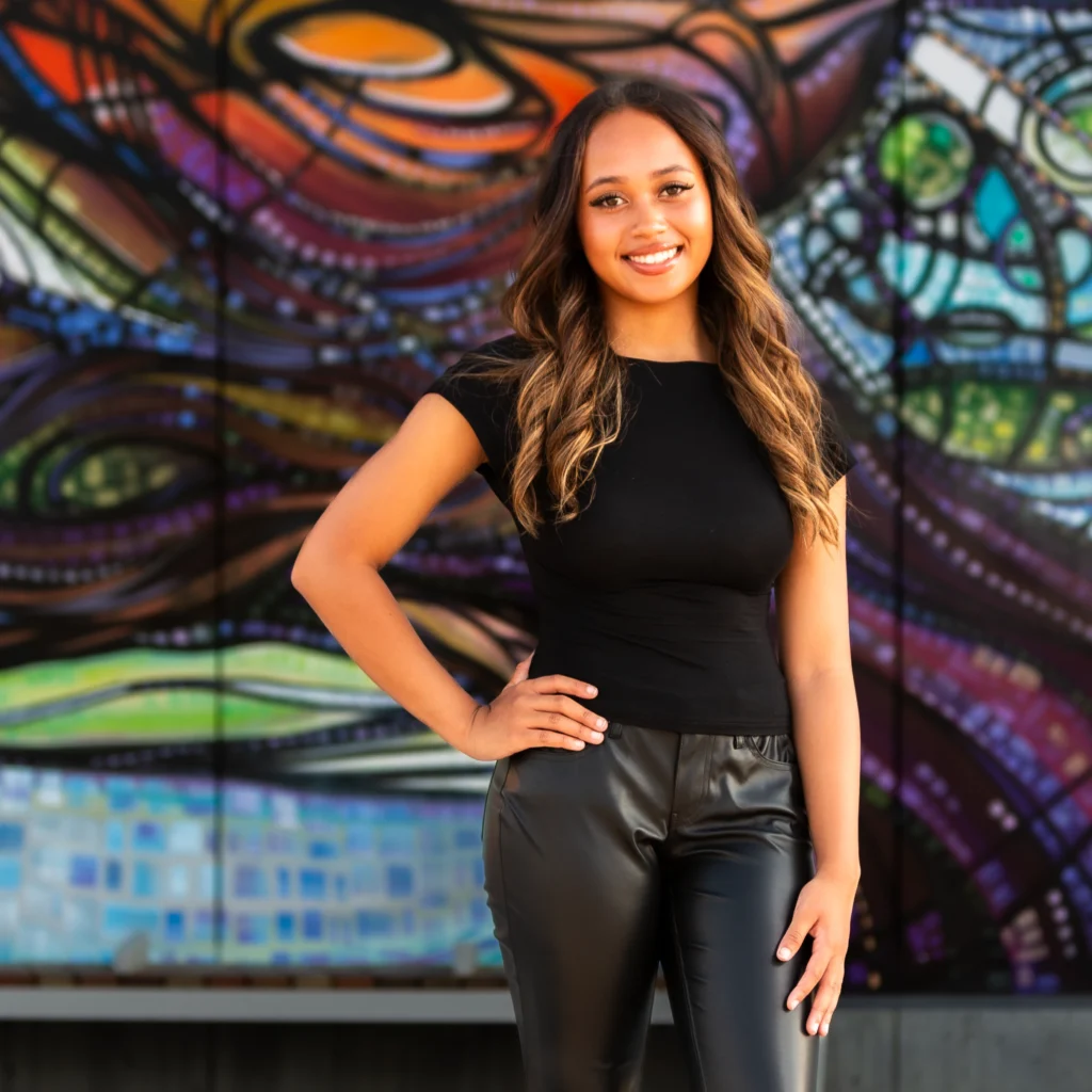 senior girl standing in black outfit smiling at camera